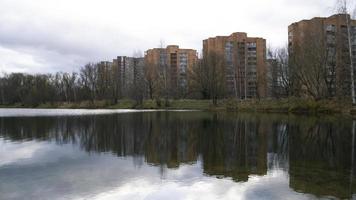 stad landskap. skog och hus runt om sjö. krusningar på vatten. stormig väder. stormig moln. himmel, solljus och träd reflekterande på vatten. hus reflekterande i vatten. foto