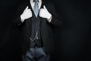 porträtt av butler eller hotell concierge i mörk kostym och vit handskar ivrig till vara av service. begrepp av elegant gästfrihet och professionell artighet. foto