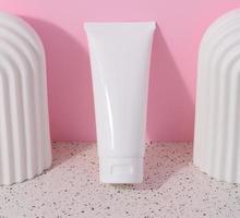 vit plast rör för flytande kosmetika på en rosa bakgrund, förpackning foto
