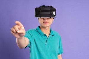 bild av asiatisk man bär virtuell verklighet glasögon på lila bakgrund foto