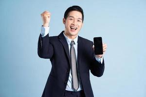 porträtt av asiatisk affärsman bär kostym på blå bakgrund foto