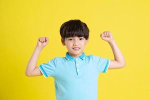 porträtt av ett asiatisk pojke Framställ på en gul bakgrund foto
