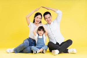 bild av asiatisk familj Sammanträde tillsammans Lycklig och isolerat på gul bakgrund foto