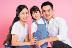 Lycklig ung asiatisk familj bild, isolerat på rosa bakgrund foto