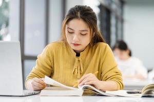 porträtt av asiatisk kvinna studerande studerar på universitet bibliotek foto