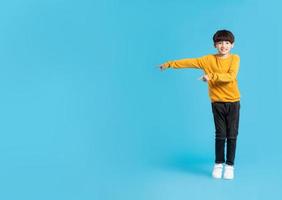 full kropp bild av asiatisk pojke Framställ på blå bakgrund foto