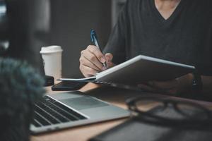 man händer med penna skrivning på anteckningsbok i de office.learning, utbildning och arbete.skriver mål, planer, göra till do och önskar lista på skrivbord. foto