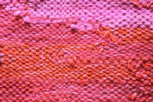 vävd rosa och orange ull tyg textur. hand stickat textil- duk bakgrund. patchwork matta bakgrund. fabrik material trådar. abstrakt design. närbild, mockup, topp se foto