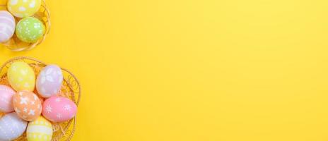 Lycklig påsk firande Semester. färgrik pastell målad ägg i korg- korg bo dekoration på en gul bakgrund. säsong- hälsning gåva kort begrepp. topp se, platt lägga, kopia Plats. foto