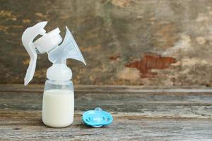 bröst pump av mjölk, napp på gammal trä- bakgrund. foto