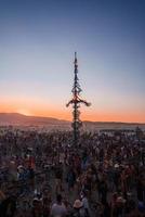 människor gående mot solnedgång på en festival i de öken- på de brinnande man festival. foto