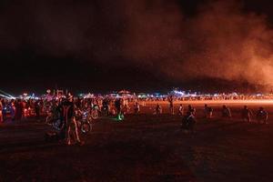 människor gående mot solnedgång på en festival i de öken- på de brinnande man festival. foto