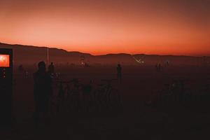 människor gående mot solnedgång på en festival i de öken- på de brinnande man festival. foto