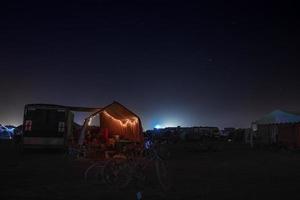 människor gående mot solnedgång på en festival i de öken- på de brinnande man festival. foto