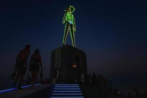 människor gående mot solnedgång på en festival i de öken- på de brinnande man festival. foto