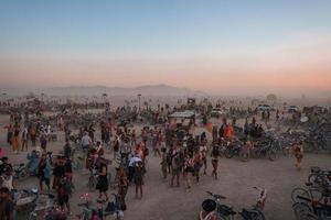 människor gående mot solnedgång på en festival i de öken- på de brinnande man festival. foto