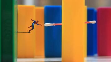 en miniatyr- mänsklig figur med de kraft av en Spindel Hoppar över en färgad blockera leksak. deras begrepp av ombilda superhjältar. foto