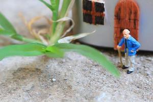 miniatyr- figur av en farfar vem är väntar i främre av de hus. foto