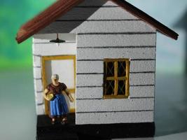 en stänga upp av en miniatyr- figur av en mor i främre av en hus. enkel Hem Foto begrepp.