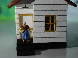 en stänga upp av en miniatyr- figur av en mor i främre av en hus. enkel Hem Foto begrepp.