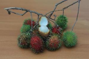 rambutan frukt som är rödaktig grön i Färg har ljuv smak isolerat på tabell. mat begrepp Foto. foto