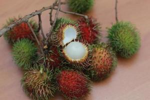 rambutan frukt som är rödaktig grön i Färg har ljuv smak isolerat på tabell. mat begrepp Foto. foto