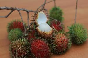 rambutan frukt som är rödaktig grön i Färg har ljuv smak isolerat på tabell. mat begrepp Foto. foto