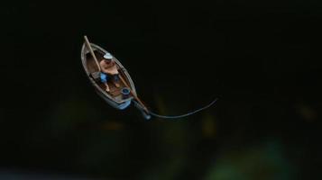 miniatyr- figur av en fiskare fiske på en sjö i en små båt. foto