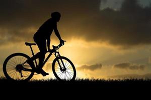 silhuetter av mountainbikes och cyklister på kvällen glatt. resor och fitness koncept. silhuett av cyklister som turnerar på kvällen cykelturnékoncept foto