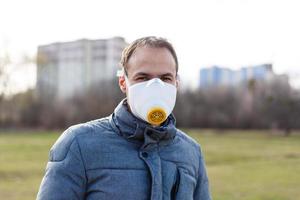 asiatisk man bär de ansikte mask på grund av till luft förorening - ung vuxen på parkera med förorening mask - person skyddande från luft förorening eller coronavirus eller covid-19 förbi bär mask. foto