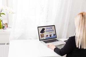 kvinna handla uppkopplad använder sig av henne bärbar dator på Hem foto