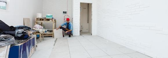 bemästra är montera golv keramisk bricka i en rum, brådskande ner och utjämning, interiör efterbehandling av lokal av en levande hus foto