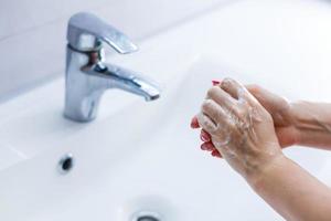kvinna tvättning händer med tvål i badrum foto