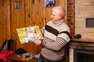 senior man innehav en Foto duk av hans barnbarn