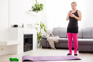begrepp av friska livsstil. stänga upp av ung kvinna händer rullande violett yoga kondition matta innan arbetssätt ut på Hem i levande rum. varje dag morgon- ritual. trä- golv, mjuk ljus foto
