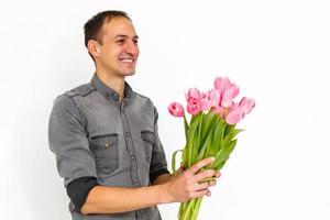 man med blommor. romantisk man med bukett av tulpaner för födelsedag. Lycklig kvinnas dag. ger bukett av blommor. stilig man ger blommor. vit bakgrund. horisontell foto.s foto