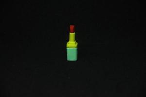 röd läppstift med gul och grön behållare rör formad suddgummi stationär verktyg för kontor eller skola förnödenheter. isolerat Foto på enkel mörk svart bakgrund.