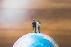 miniatyraffärsmän som står på en världskarta med en brun bakgrund foto