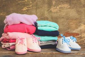 bebis skor, Kläder och nappar rosa och blå på de gammal trä- bakgrund. tonad bild. foto