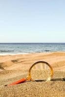 förstorande glas i de sand på de strand foto