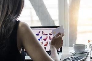 kvinna som rymmer ett kreditkort på bärbara datorn och handlar online-koncept