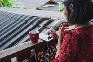 kvinna på sin telefon med en kaffe foto