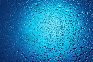 vatten droppar på glas på en blå bakgrund. foto