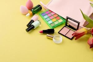 ljus sommar ögonskugga palett och smink Produkter i rosa kosmetisk väska på grön bakgrund foto