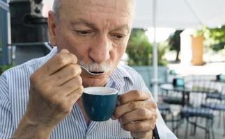 äldre man dricka espresso kaffe på ett utomhus- Kafé foto