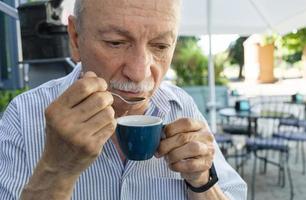 äldre man dricka espresso kaffe på ett utomhus- Kafé foto