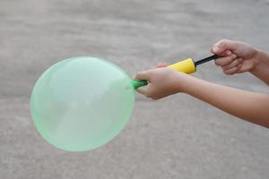 blåser grön ballong förbi hand luft pump, blåses upp luft till ballong begrepp, barn spela, leksak och Utrustning till spela roligt spel eller förbereda fest. foto