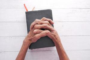 äldre kvinnor som håller en bibel i händerna och ber. foto