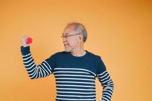 senior manlig med hantel för övning aktiva livsstil i pensionering liv hälsa vård på Färg bakgrund. foto