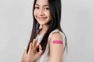 Lycklig ung kvinna visa ok tecken efter få en vaccin. som visar axel med bandage efter tar emot vaccination, besättning immunitet, sida effekt, booster dos, vaccin pass och coronavirus pandemi foto